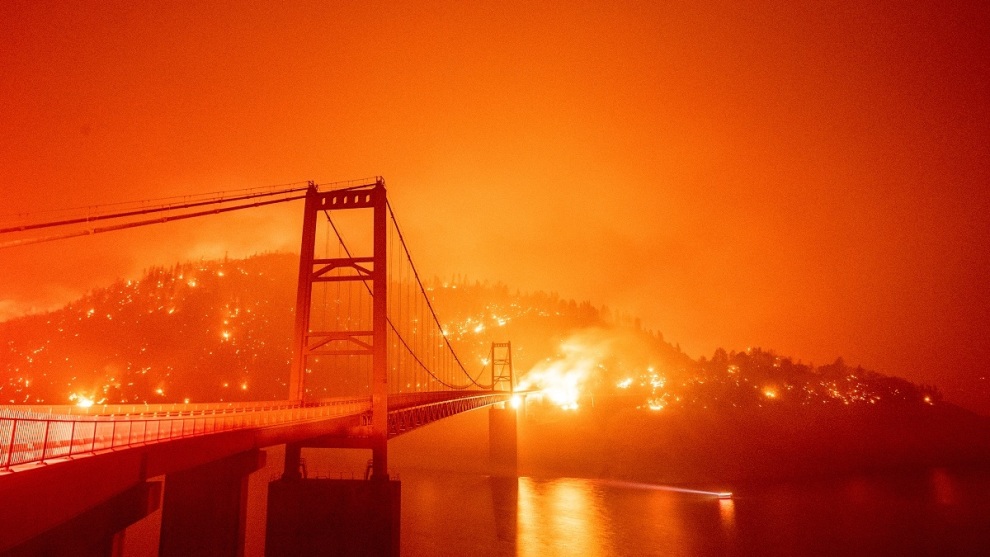 &copy; Josh Edelson. A boat motors by as the Bidwell Bar Bridge is surrounded by fire in Lake Oroville during the Bear fire in Oroville, California on September 9, 2020.