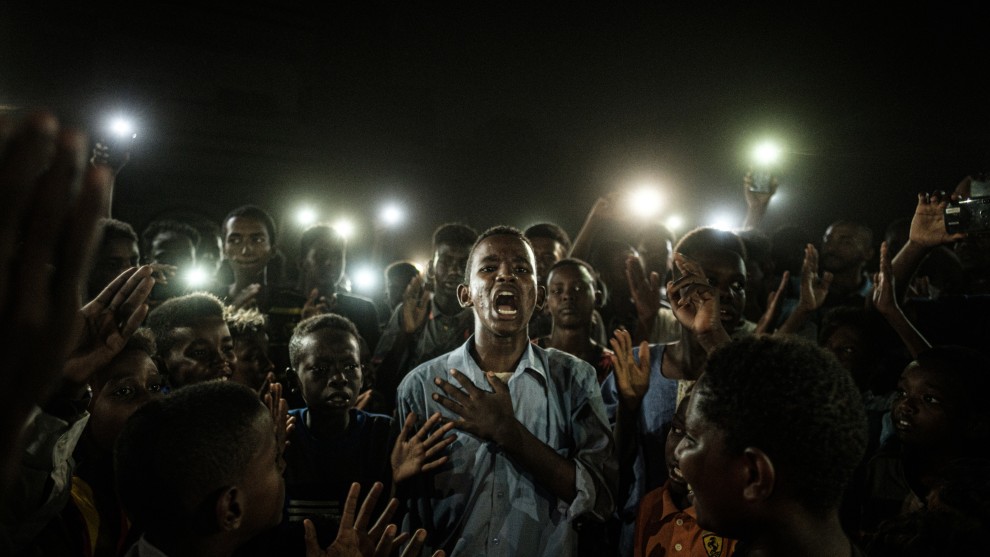 WINNER: WORLD PRESS PHOTO OF THE YEAR . &copy; Yasuyoshi Chiba, Agence France-Presse. A young man, illuminated by mobile phones, recites a poem while protestors chant slogans calling for civilian rule, during a blackout in Khartoum, Sudan, on 19 June.