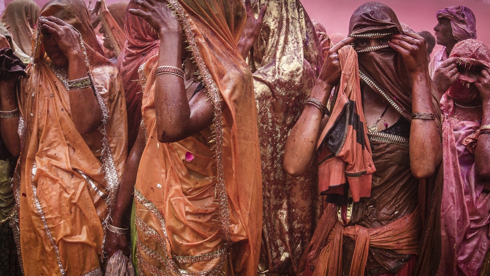 Women at Huranga Holi Festival, Mathura, India. Shooting Holi is easily one of the most intense photographic experiences I&rsquo;ve had. The festival reached its climax at the Badadev Dauji Temple when the temple was flooded with water. A procession of gods is accompanied by men throwing buckets of water on the watching women who in turn tear the shirts off the men, roll them up, then beat anyone within range with the wet, rolled up shirt. And yes, it hurts! For about 40 minutes I was buffeted around by the milling crowd as water and powder was splashed around, but being on the temple floor provided the intimate point of view that puts the viewer right there. Of course, you have to be prepared for such opportunities with an appropriate camera cover. I used a soft Aquatech rain cover which protected the camera perfectly, but I eventually had to stop shooting when I ran out of dry cloth and tissues to wipe the water off the UV filter on the lens.