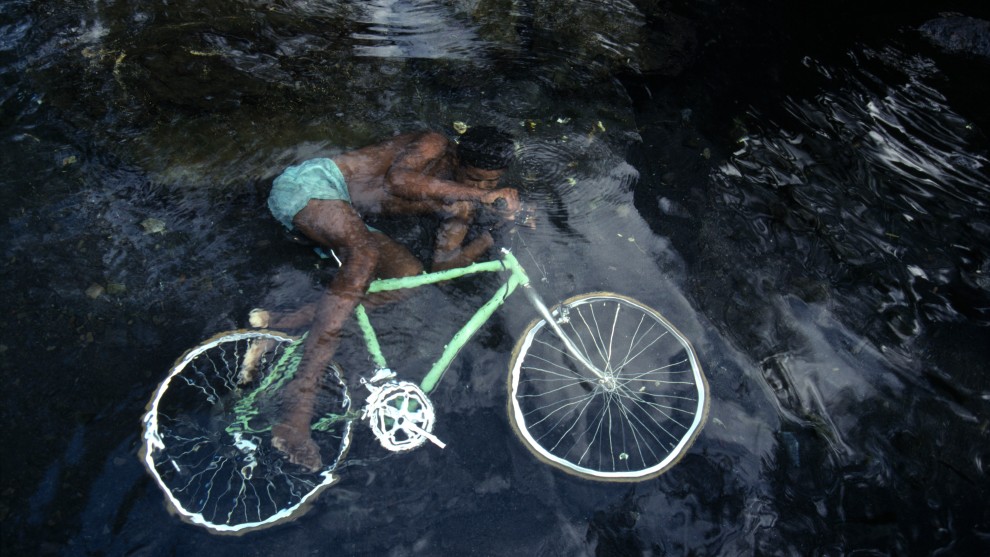 Bruno Barbey, A boy plays in the Rivi&egrave;re des Galets. R&eacute;union. 1991. &ldquo;When traveling and photographing, you have to establish human contact while remaining discreet. Luck sometimes plays a role too. This boy was cleaning his bicycle in a spring and playing with it; my luck was that he wore green shorts matching the color of
his bike. The result is a strange and surreal setting in which the
boy seems to ride his bicycle under water. Photography is the only language that can be understood anywhere in the world.&rdquo; &copy; Bruno Barbey/Magnum Photos