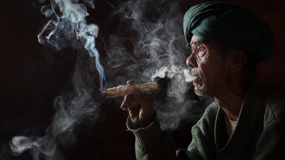 In this low-light portrait, the local Burmese man was sitting on the floor of a dark temple, but close to the doorway which provided a strong, focused light in an otherwise dark scene. Smoke illuminated by light is always very powerful in photography.
