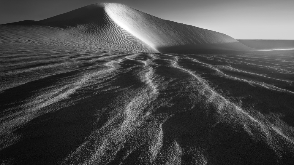 I inverted the centre column of the tripod so the camera was upside down and just centimeters from the sand to create the dramatic foreground appearance of these ripples in the sand. All of them lead into a central point. Sony A7R, 16-35mm f/2.8 lens. 1/40s @ f11, ISO 200.&nbsp;