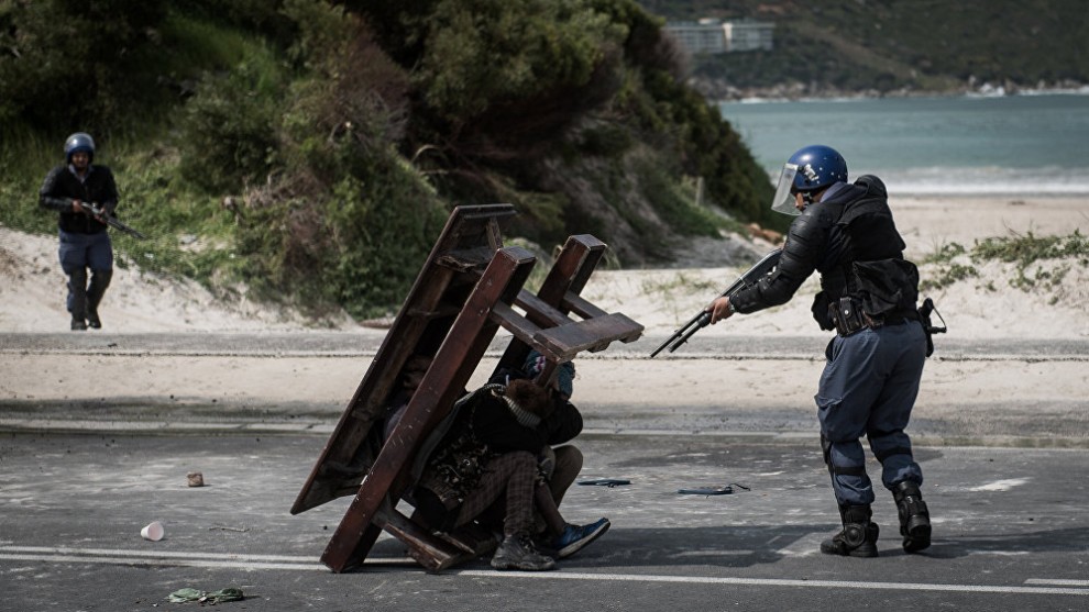 Photo: Justin Sullivan, South Africa. First place, News, Single, 2018 Andrei Sennin International Press Photo Contest.
A police officer points his gun at&nbsp;three occupants during a protest over&nbsp;fishing quotas led to&nbsp;three days of&nbsp;unrest in&nbsp;the community.