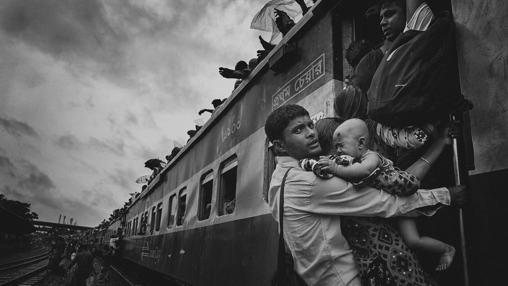 Third place, People: &lsquo;Challenging Journey&rsquo; by MD Tanveer Hassan Rohan. &ldquo;This photograph was taken from Dhaka&rsquo;s airport rail station during the Eid vacation. People were returning to their village homes to spend Eid with families, and the rush at the last hour was immense. &ldquo;One man caught my attention: he was dangling on a train&rsquo;s handle with his family, trying to get inside the train. At that time, rain started and the train began to slowly move. The family had tickets to board the train, but couldn&rsquo;t get to their seats. &ldquo;There are many people like him, who come to Dhaka for work-leaving their families and home villages-so when they get vacation, they don&rsquo;t want to miss the opportunity to spend time with dear ones, no matter what.&rdquo;