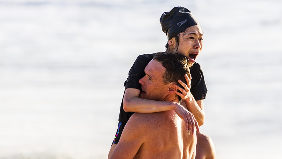 A distraught woman is assisted by a lifeguard after being rescued from the raging surf. &copy; Jenny Evans