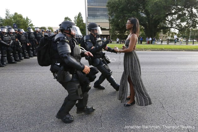 Contemporary Issues - First Prize, Singles. Taking A Stand In Baton Rouge. Lone activist Ieshia Evans stands her ground while offering her hands for arrest as she is charged by riot police during a protest against police brutality outside the Baton Rouge Police Department in Louisiana, USA, on 9 July 2016. Evans, a 28-year-old Pennsylvania nurse and mother of one, traveled to Baton Rouge to protest against the shooting of Alton Sterling. Sterling was a 37-year-old black man and father of five, who was shot at close range by two white police officers. The shooting, captured on a multitude of cell phone videos, aggravated the unrest coursing through the United States in previous years over the use of excessive force by police, particularly against black men. &copy; Jonathan Bachman, Thomson Reuters
