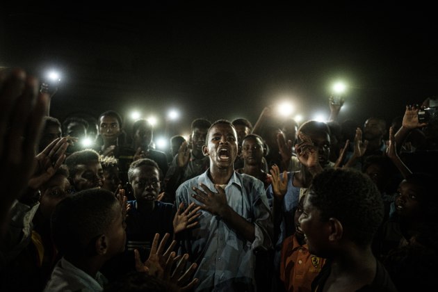 WINNER: WORLD PRESS PHOTO OF THE YEAR . &copy; Yasuyoshi Chiba, Agence France-Presse. A young man, illuminated by mobile phones, recites a poem while protestors chant slogans calling for civilian rule, during a blackout in Khartoum, Sudan, on 19 June.
