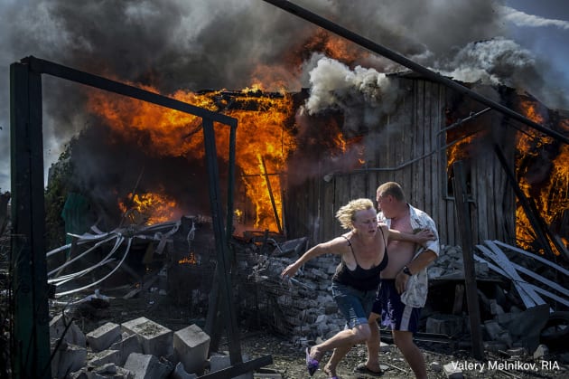 Long-Term Projects - First Prize. Black Days Of Ukraine. Civilians escape from a fire at a house destroyed by an air attack in the Luhanskaya village. &copy; Valery Melnikov, Rossiya Segodnya.