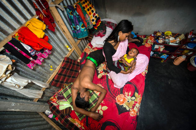 From the series, "The Longings of the Others". Kajol with her 6-month-old baby, Mehedi, and a customer on her bed. Two weeks after birth of Mehedi, she was forced to have sex again with customers. Because of the baby, her business is not good. &copy; Sandra Hoyn, Germany, 1st Place, Professional, Daily Life, 2017 Sony World Photography Awards.