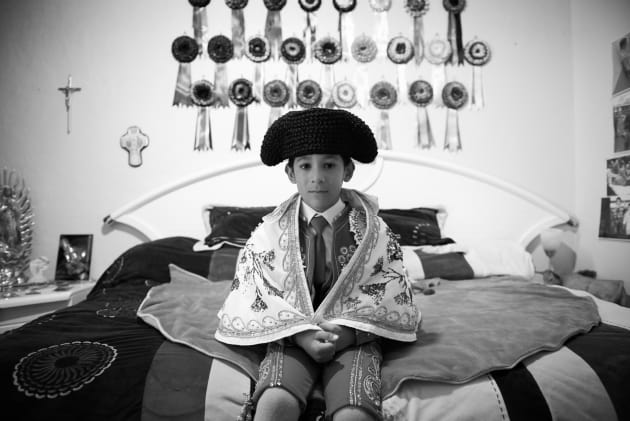 Salvador, aged 6, sits on his bed as he waits to depart for the afternoon bullfight, in Plaza Mexico, from the series, "The Little Bullfighters of Mexico". &copy; Christina Simons, Iceland, 2nd Place, Professional, Daily Life, 2017 Sony World Photography Awards.