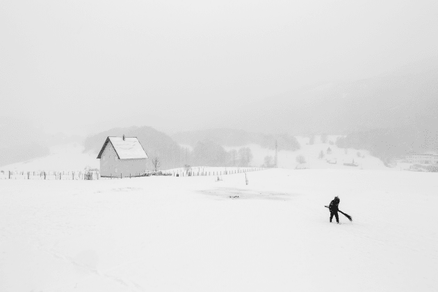 Shepherd, from the series, "Whiteout". In the North of Montenegro, a shepherd is walking to his herd of sheep with a self-made broom in his hand. The broom was used to wipe off the snow lying on the back of the sheep. &copy; Frederik Buyckx, Belgium, Photographer of the Year, Professional, Landscape, 2017 Sony World Photography Awards.