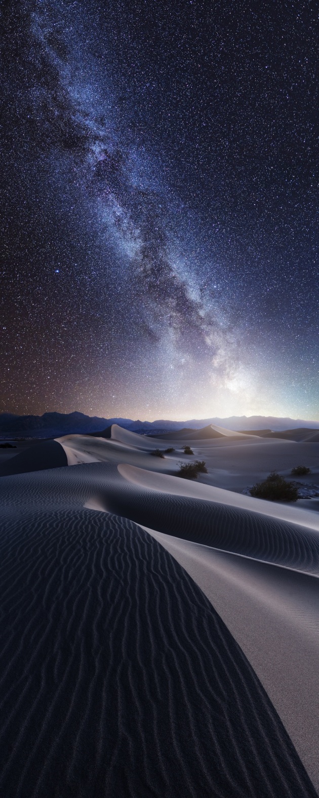 &copy; Mads Peter Iversen, Denmark. 2017 EPSON Digital Art Prize 1st Place.
"'Sand and Stars' is a composite photo from Death Valley National Park.We spent four days in this fantastic environment and went into the Mesquite Sand Dunes twice. I didn&rsquo;t manage to capture a proper Milky Way photo while in the dunes, so I composited one from Badwater Basin &ndash; also located in Death Valley National Park.
I found this beautiful curve in the dunes, which I could extend with the Milky Way to create one long S-curve. On top of that the Milky Way lines up with the foreground sand curve, making two parallel lines. All this makes one strong and simple composition.
I&rsquo;ve been fascinated with astronomy my entire life and fusing the Milky Way with a sandy foreground seems obvious to me. It&rsquo;s fascinating that there are more stars in the universe than grains of sand on planet Earth!"