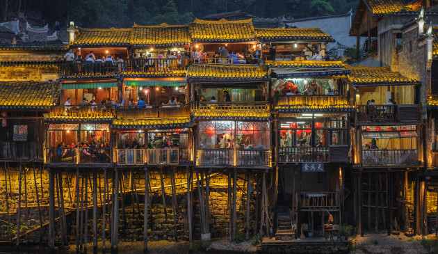 &copy; Peng Li
1st Prize &ndash; Night Photography category. This photograph was taken of an ancient Chinese &lsquo;Diaojiaolou&rsquo; house in the town of Fenghuang, located near the Tuojiang River in Hunan province. Diaojiaolous are often used as hotels or restaurants in Hunan province, due to their great charm and beauty. As the night falls, countless red lanterns provide light inside the Diaojiaolou, giving a priceless and surreal view of past and present in one photograph.