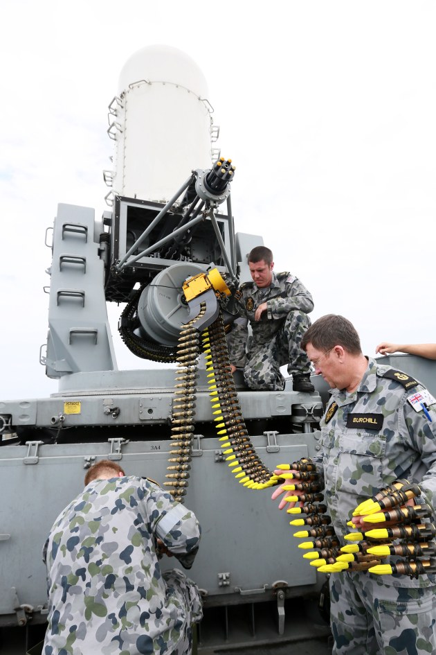 Chief Petty Officer Electronics Technicians Tony Burchill (lower right) and Leading Seaman Richard Curtain (on mount) feed 20mm rounds to the ammunition drum of the Phalanx Close In Weapons Systems aboard HMAS Sydney (FFG 03). [Defence]