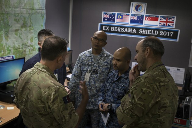 RAAF Wing Commander Colin Would (left) from exercise control inside Headquarters Integrated Area Defence System gives direction to key staff members during Exercise Bersama Shield 17 at RMAF Butterworth, Malaysia.