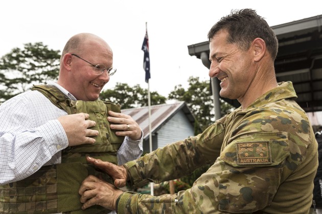 Australian Army soldier Corporal James Boulton (right) helps his civilian employer, Mr Robert Warburton, try on body armour. The light weight of XTEK's SAPI plates was a major selling point.
Defence