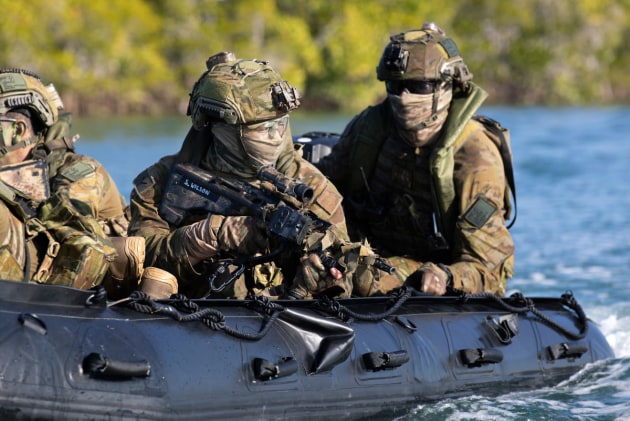 A sniper scans the shoreline during a riverine insertion. Defence