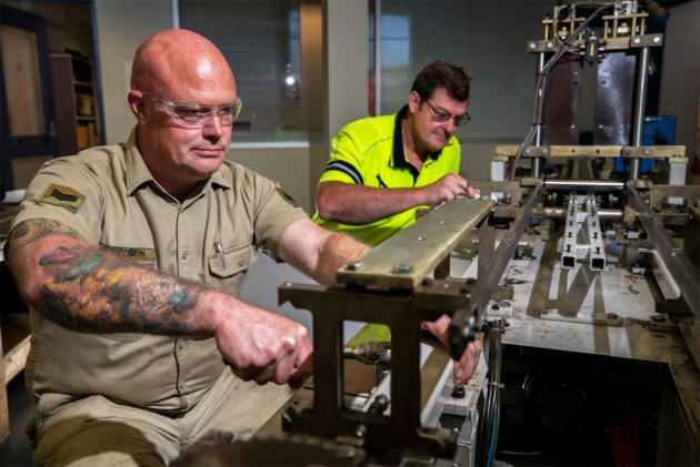 Sergeant Steven Davidson and Mr Bob Neighbour repair a medical mask manufacturing machine so it can return to service as quickly as possible. (Defence)