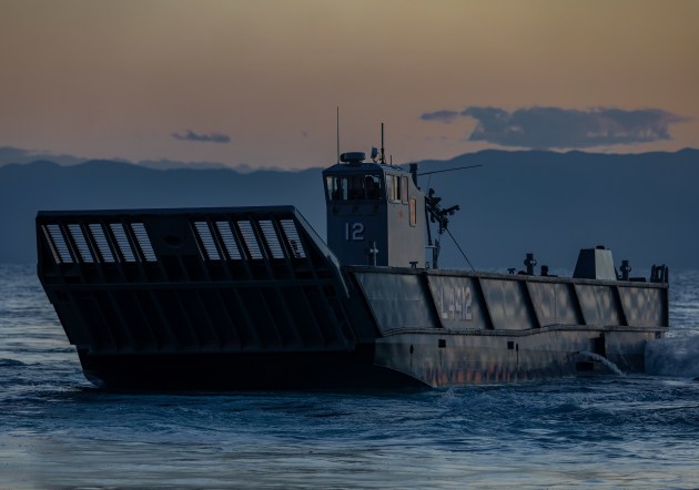 A landing craft positions itself to enter the dock well of HMAS Adelaide at sunset. (Defence)