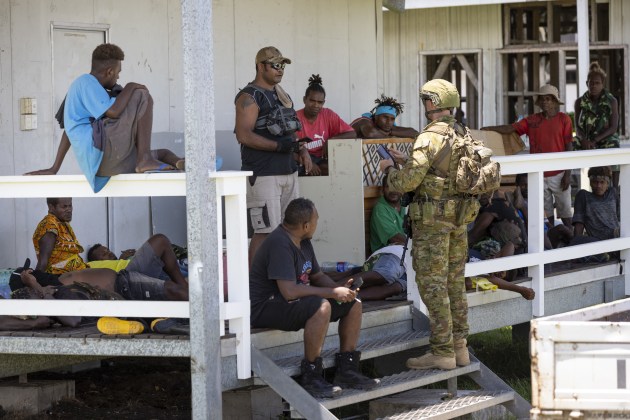 An Australian Army soldier from the Joint Task Group 637.3 talks with local citizens during a community engagement patrol through Honiara, Solomon Islands on 27 November 2021. (Defence)