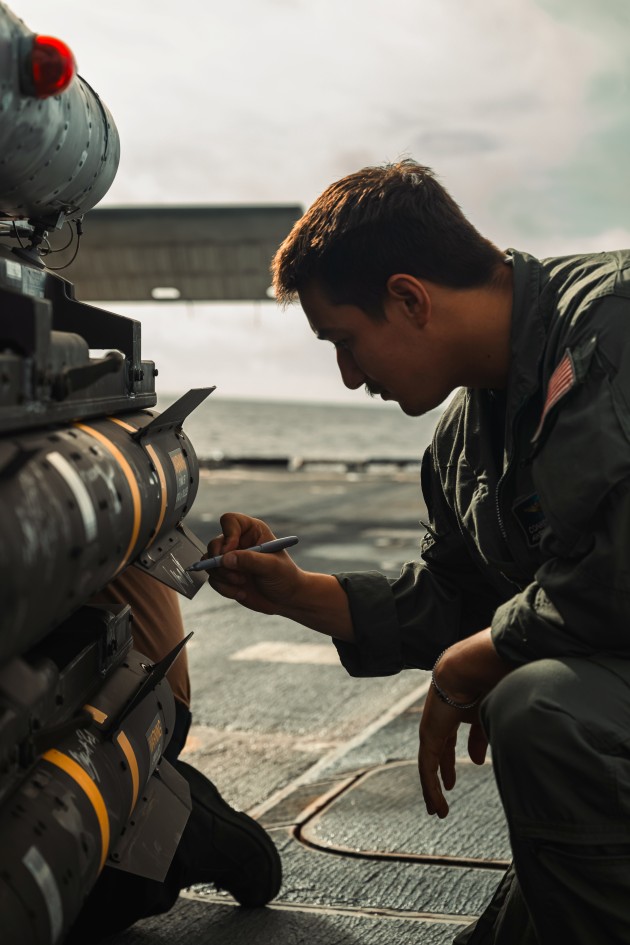 Air Crewman (Helicopter) 2nd Class, attached to the Helicopter Maritime Strike Squadron (HSM) 50 "Valkyries" detachment aboard Arleigh Burke-class guided missile destroyer USS Thomas Hudner (DDG 116), signs an AGM-114 hellfire missile in preparation for the Sink Exercise in support of UNITAS 2025, the 66th iteration of the world's longest-running multinational maritime exercise. 

Credit: Petty Officer 1st Class Hannah Mohr / US Defense