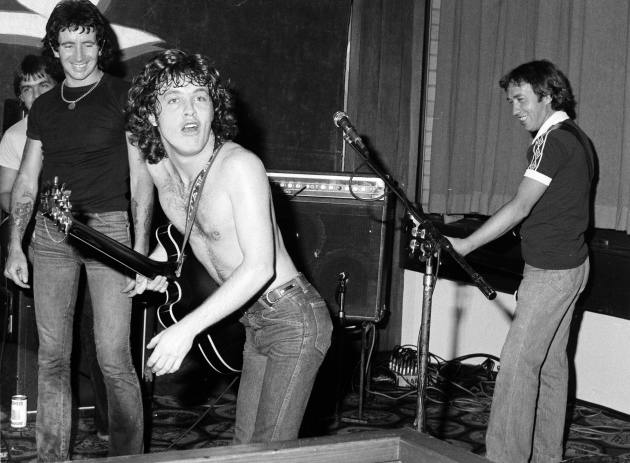 AC/DC - Angus (almost) bares all, as Bon and brother, George look on. Strata Motor Inn, Cremorne, 1979. &copy; Philip Morris.