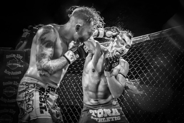Muay Thai fighter, Jun Lee is struck in the
head by Elliott Compton, showing his
fang-design mouthguard. &copy; Matt Palmer.