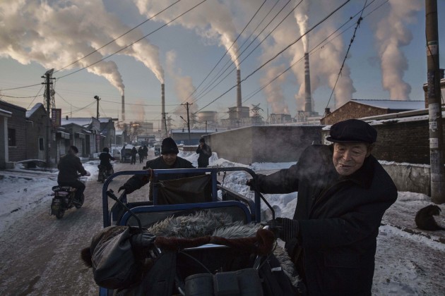 Daily Life, 1st prize singles. &copy; Kevin Frayer, Canada, 2015, Getty Images. China's Coal Addiction.
Chinese men pull a tricycle in a neighborhood next to a coal-fired power plant in Shanxi, China, on 26 November 2015.