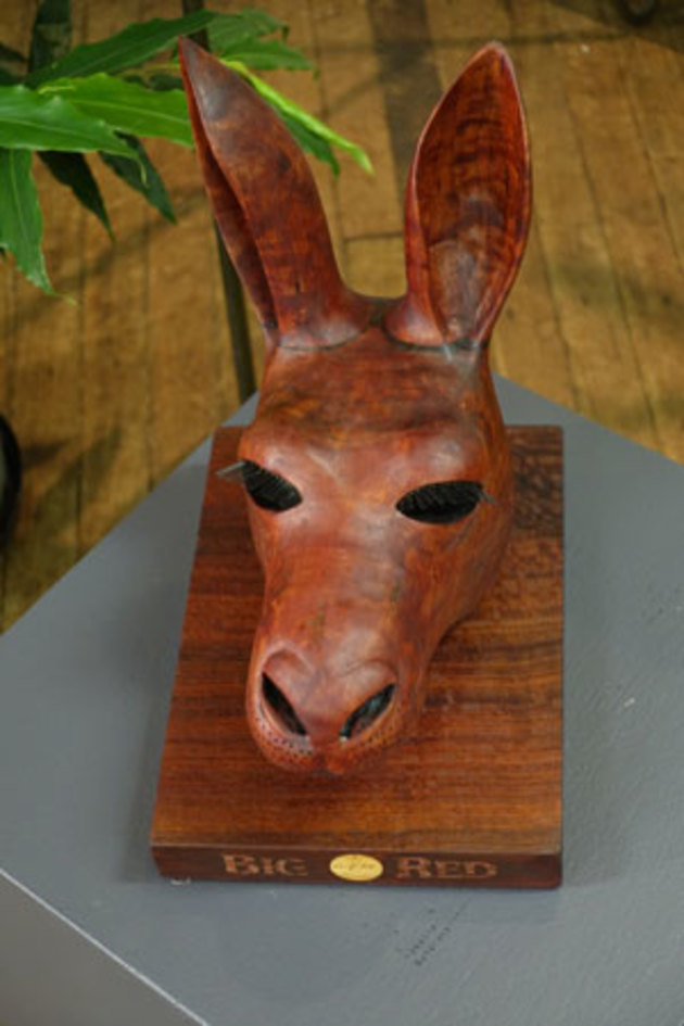 Doug Bell, Head of a Big Red. &lsquo;This sculpture attempts to convey the essence of the aristocratic aloofness so often seen when a large male red kangaroo surveys its territory. The timber was cut from a bushfire burnt log of Australian redgum, Eucalyptus camaldulensis, which has interlocked grain resulting in rippled or quilted patterns. Additionally, the grain was also fire hardened. Because of this the carving gouges and chisels are constantly attempting to cut "against the grain", adding a degree of difficulty which does not occur with straight-grained timbers. The redgum was of indeterminate age but had been lying in a paddock for about 30 years since the Ash Wednesday fires in South Australia. Redgum&rsquo;s strength, colour and rich grain seemed the logical choice to portray this unique and iconic Australian marsupial with ears cocked, taking in every sight and sound around it.&rsquo;