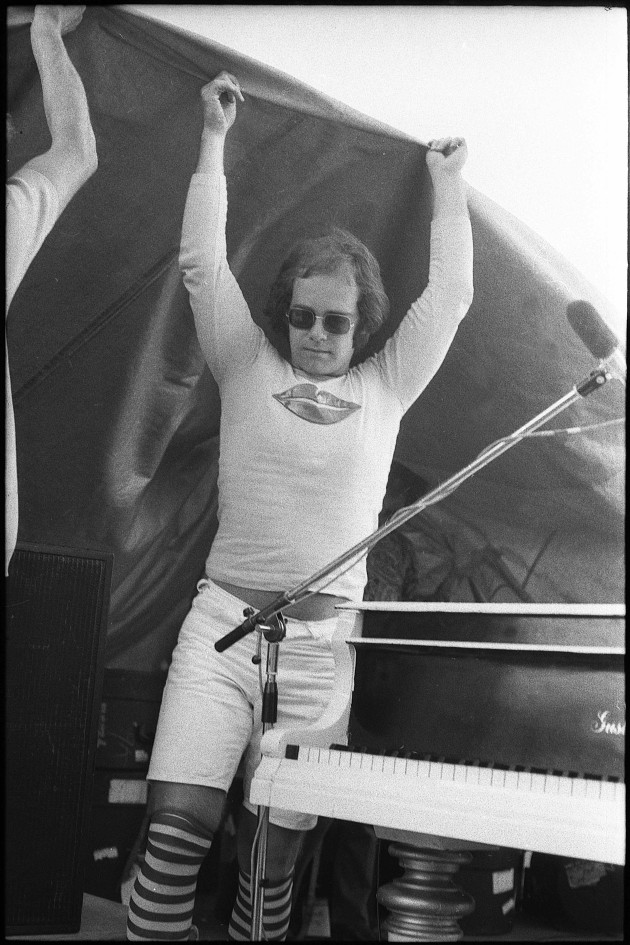 Elton John stretching for cover during a freak storm. Randwick Racecourse, Sydney, 1971.&copy; Philip Morris.