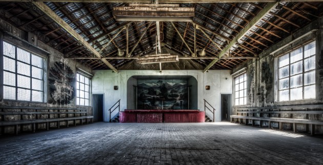 Entertainment room. This is at the Victoria Road entrance to the plant. A big, long room where the hard-working power plant staff cooled down after a hard day next to the furnaces. Kind of looks like the ultimate man cave in a power station 50 years ago. It has built-in speakers in the walls, a kitchen and even still a couple of old ping pong tables and something that looks like table soccer but from 50 years ago. No Wi-Fi unfortunatley. Notice the old murals on the wall and the stage? Most of the side  wall murals have been washed away from when the asbestos roof was removed a few years ago. &copy; Brett Patman