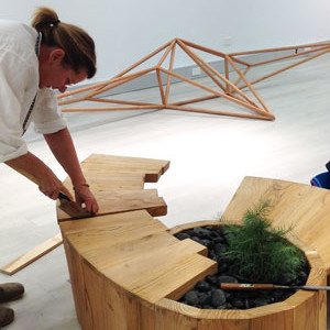 Katalin Sallai installing her 'Witness Tree from Kingston' bench made from Himalayan cedar with Matthew Harding's piece at the rear. Photo: Monica Styles
