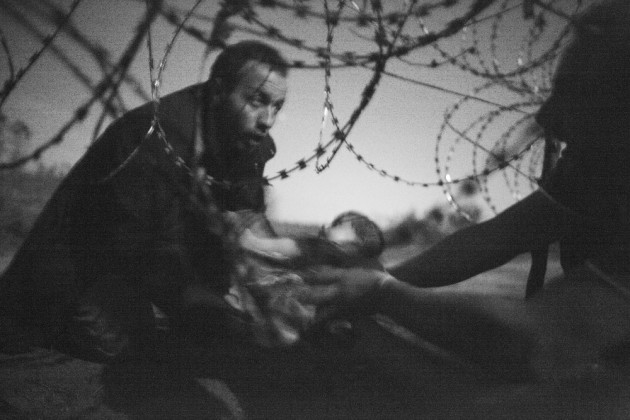 World Press Photo of the Year. &copy; Warren Richardson, Australia, 2015. Hope for a New Life. A man passes a baby through the fence at the Serbia/Hungary border in R&ouml;szke, Hungary, 28 August 2015.