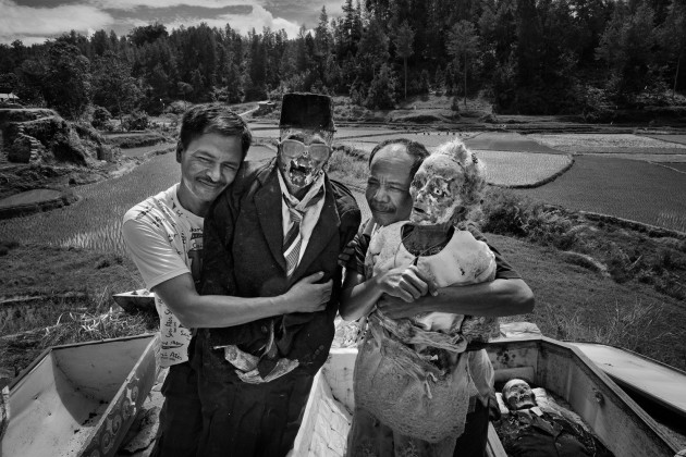&copy; Alain Schroeder, Belgium. WINNER, TRAVEL PHOTOGRAPHER OF THE YEAR 2017. Dumbia village, Pangala, Toraja, Sulawesi Island, Indonesia. Ma' Nene ceremony. Brothers Micha from Jakarta and Misi from Makassar embrace their parents, father Tumaang and mother Rara. The grave house is located on top of a hill overlooking the rice fields.