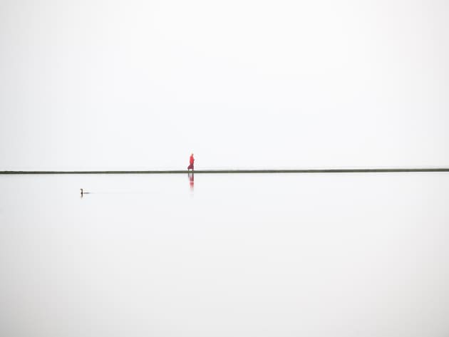 &copy; Craig Easton, UK. 
Winner, Land, Sea, Sky portfolio.
West Kirby, Wirral, UK. A lone Buddhist monk walks around
the boundary wall of the West Kirby Marine Lake.
