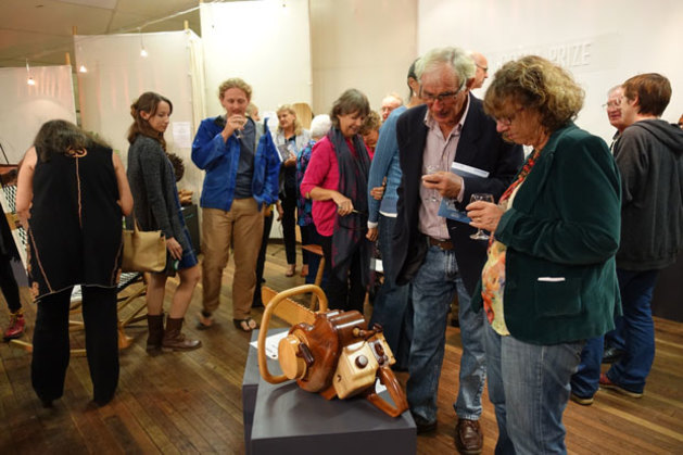 Opening night visitors take a closer look at David Harriman's prize-winning Noise and Dust chainsaw replica.