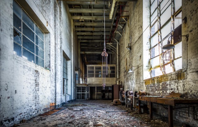Workshop. An old engineering workshop, probably used to be filled with lathes, milling machines, drills... The real stuff from when the workers made new machinery parts when they broke instead of buying replacements. All that remains today are three ducted, bench grinders and a lonely old chainblock, hanging above a floor comprised of broken glass, rusted pieces of metal, paint flakes and chunks of rotting wood that have fallen from way above. &copy; Brett Patman