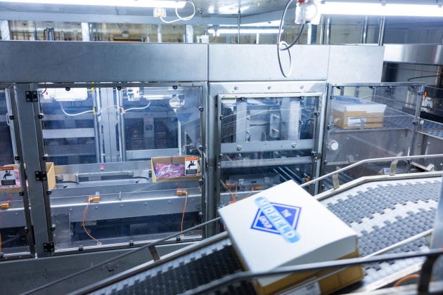 MHM&rsquo;s solution for Midfield include a Six-Mag Carton Lidder (pictured) to automatically places and seals lids on cartons; an SSO Plate Freezer, each with capacity to freeze 3072 cartons in 24 hours; an Automated Storage and Retrieval System (ASRS), for chilled and frozen products, and a Three-Cell Robotic Palletising System with auto-check scanning, stretch wrapping and labelling.
