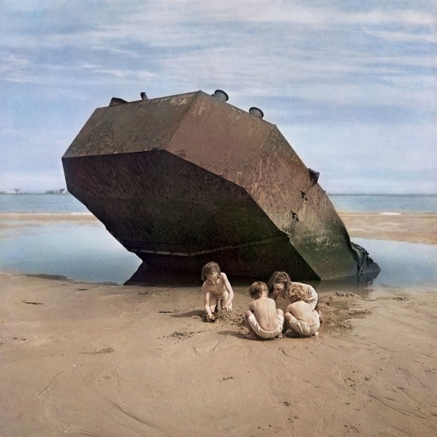 Children play among the wreckage of the D Day invasion. Normandy, France, 1947. &copy; David Seymour / Magnum Photos. 
&ldquo;David &lsquo;Chim&rsquo; Seymour returned to Europe on an assignment for 'This Week' magazine in April 1947. He travelled to the Normandy beaches in order to revisit the location where the Allied D-Day invasion took place on June 6, 1944. Chim&rsquo;s particular interest in how the young dealt with and reacted to years of conflict led him to these kids playing happily on the beach near the ominous steel shell of an abandoned fortification.
The four children seem deeply engrossed in their imaginative plan to make a sand castle or some other creation, somehow ignoring what is hanging over their heads. The terror of D-Day lingers over this image of children and calm weather, with clouds softening the sunshine."
&ndash; Ben Shneiderman, nephew of David &ldquo;Chim&rdquo; Seymour