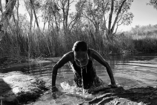 Water is life and Chrissy respects the ancient knowledge and the custodian of this waterhole.  Before diving into the living water, Chrissy is advised by an elder to rub a stone under her armpits and throw it into the water to give her safe passage. &copy; Ingetje Tadros.
