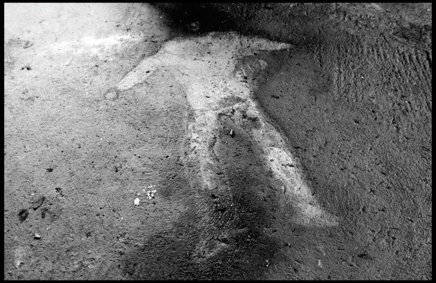 &copy; Gary Knight. The outline of the body of Kola Dusmani, who according to criminal investigators, was killed by Russian paramilitaries in a small village outside Gjakove, Kosovo. After he was murdered, the house where the crime was committed was burned. Soot and ashes covered the body. Following the war, the family that owned the home returned and Dusmani&rsquo;s remains from their living room. This outline could not be removed. Today it is concealed by a carpet.