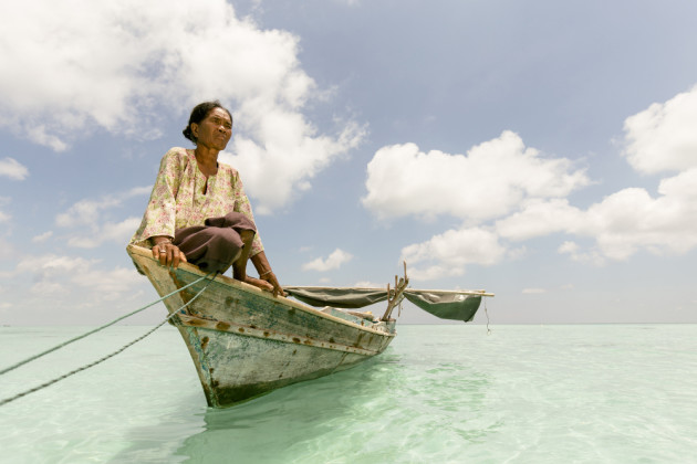 A Bajau Laut woman with her husband, fishing off Denawan Island. &copy; Mark Lehn.