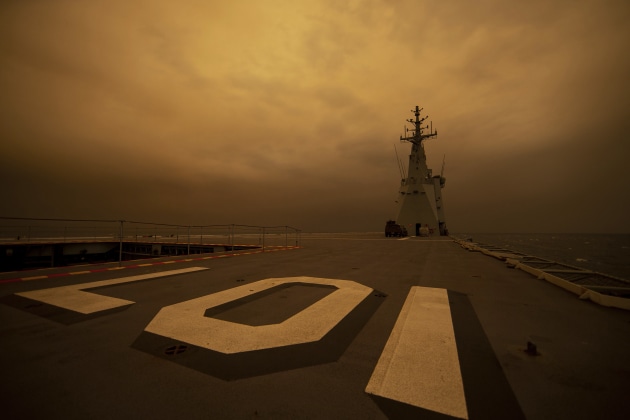 HMAS Adelaide arrives off the coast of Eden under a cloud of smoke. (RAN via Twitter)