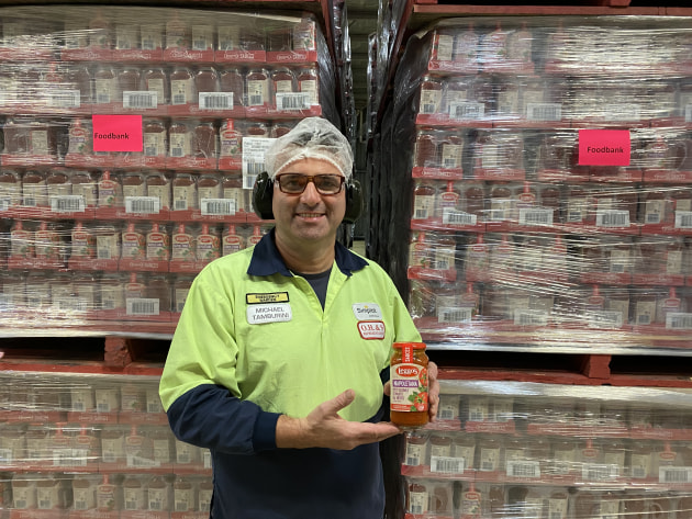 Simplot Australia employee with Leggo&rsquo;s Napoletana Sauce stacked and ready for Foodbank