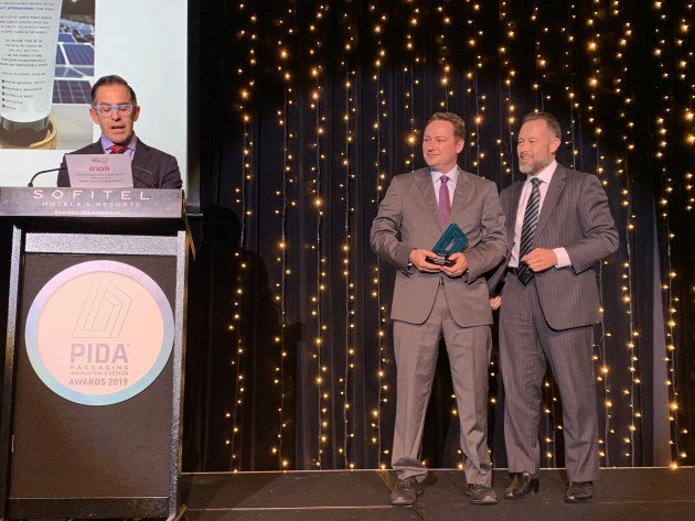 Craig Wellman, CEO of Wellman Packaging (right) congratulates Aleks Lajovic, MD Impact International, winner of a gold PIDA in the Health, Wellness and Beauty category, while Anthony Peyton reads the citation.