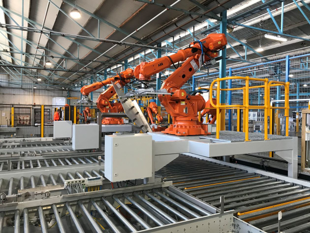 Magazine pick robots showing part positioning nest. Two ABB IRB6700 robots pick from the magazines placing the side panels into a location nest where they are re-picked by two ABB IRB2600 robots for assembly on the oven.