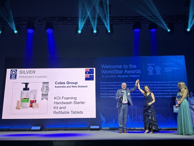 John Bigley, AIP president, accepts the Silver Presidents Award on behalf of Coles from WPO President Luciana Pellegrino.
