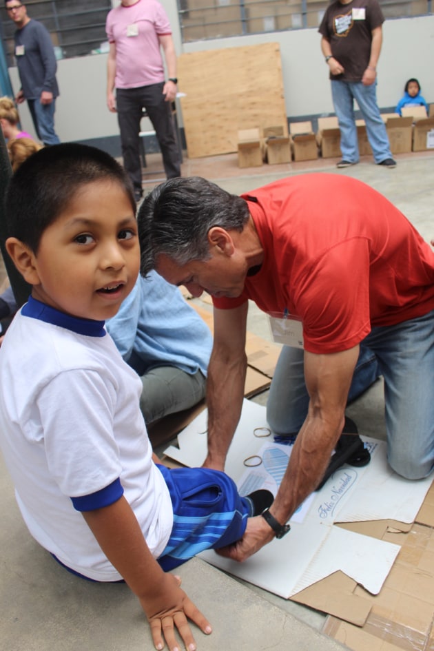 Toms CEO, Jim Alling, fitting a child with a pair of shoes.