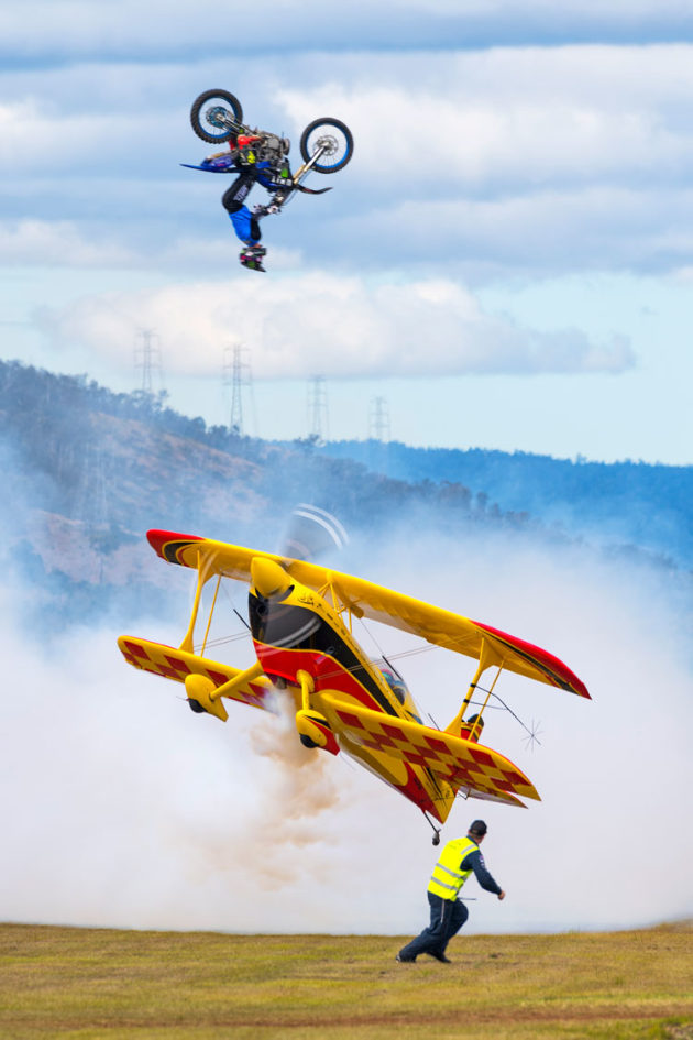 Paul Bennet slides his Wolf Pitts below a leaping motorbike as the ground crew exits stage right. (John Absolon)