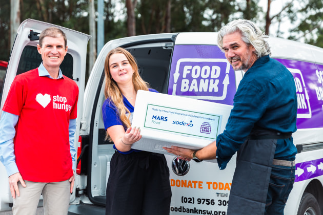 Geoff Webster, General Manager Strategic Accounts at Sodexo (left); Bill Heague, GM of Mars Food Australia (right); and Jordynn Ardron, School Breakfast4Health and Agencies Coordinator at Foodbank NSW (centre) load up a Foodbank van with donated meals. Source: Mars Food Australia